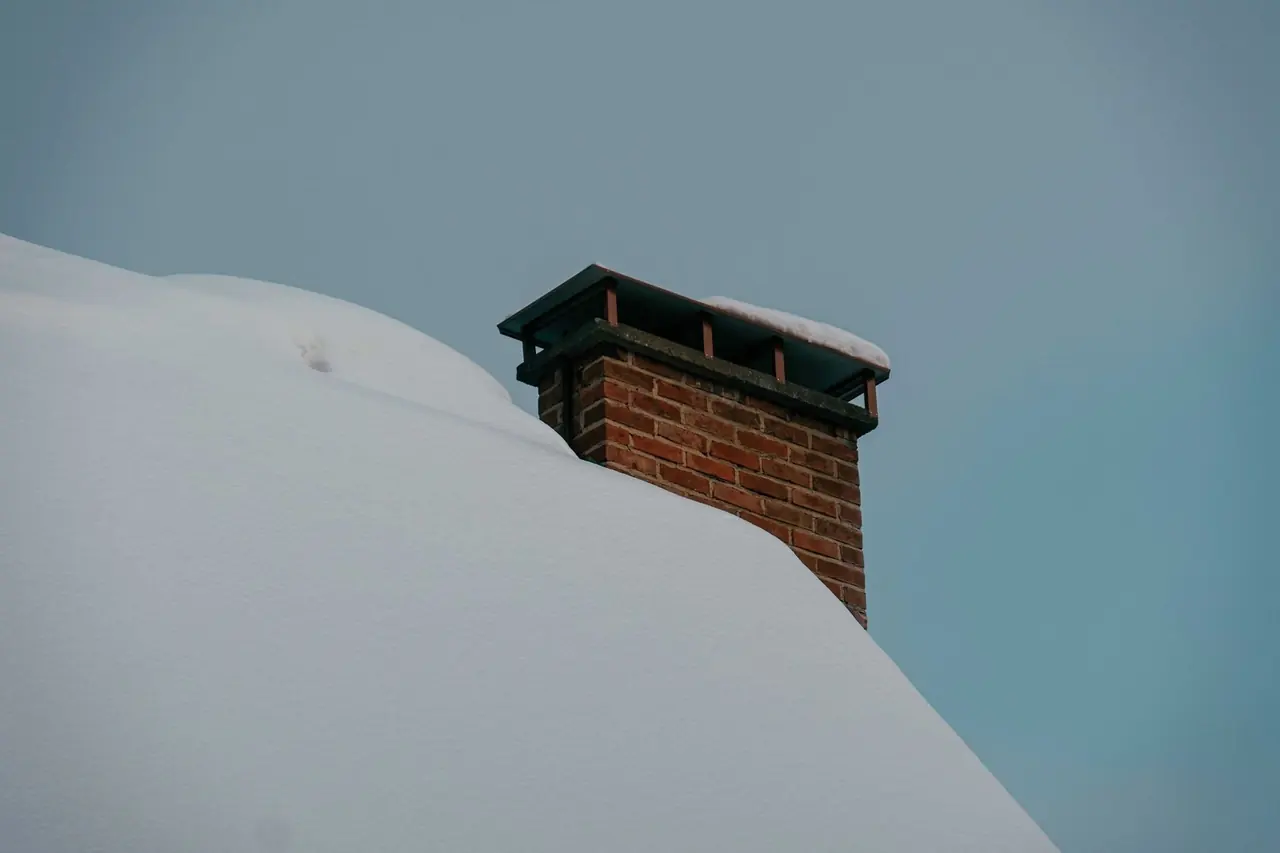 Cheminée de brique sur un toit couvert d'une épaisse couche de neige