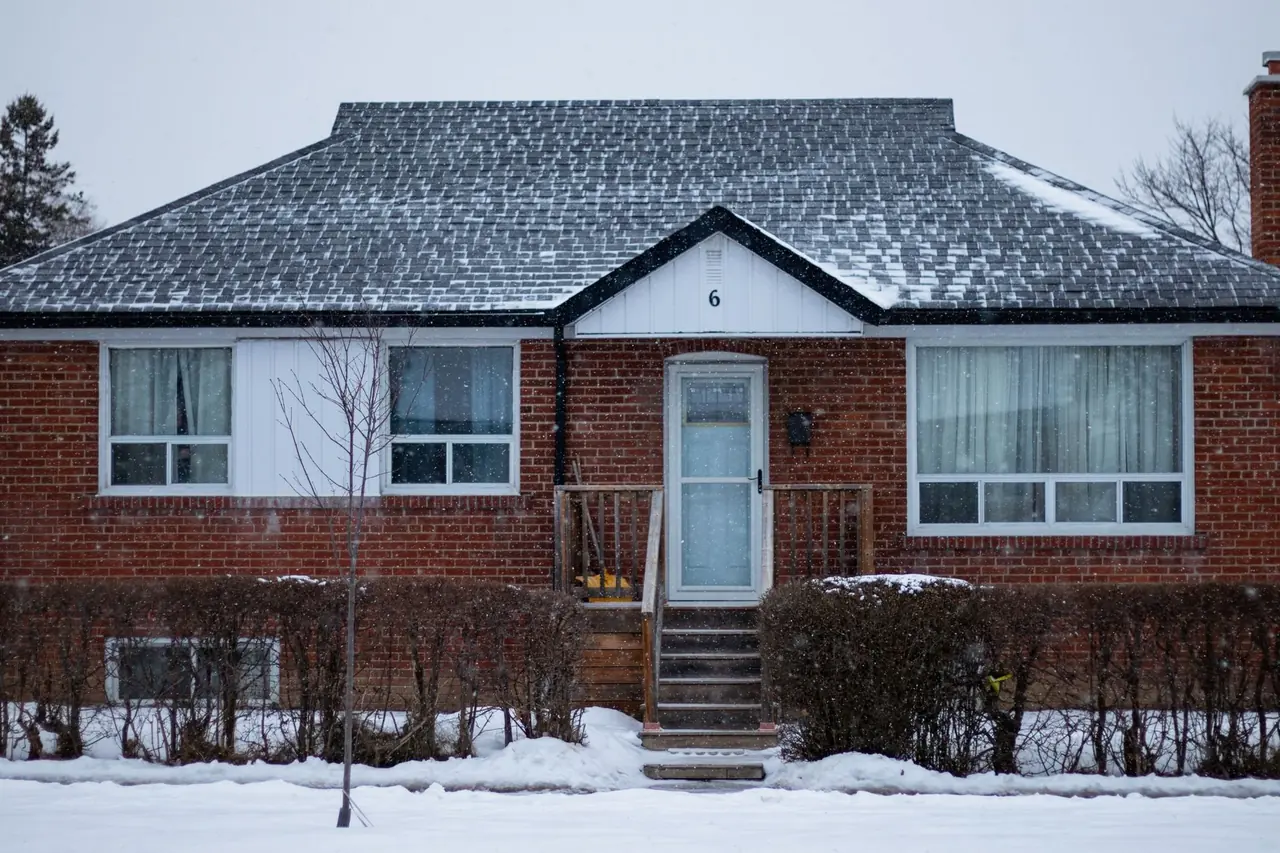 Bungalow de brique rouge avec marches d'entrée sous une légère neige