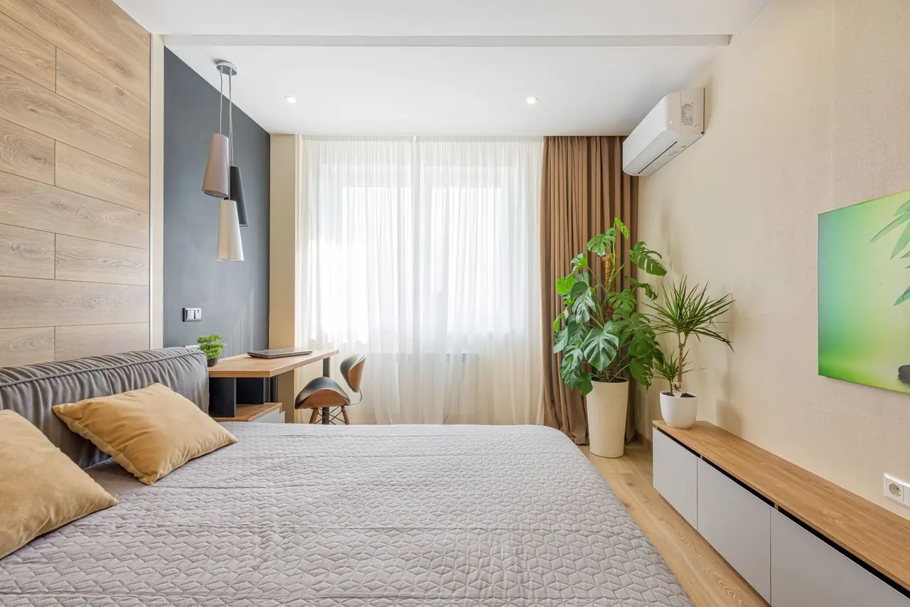 Chambre aux tons de bois chaud avec thermopompe murale au-dessus du rideau