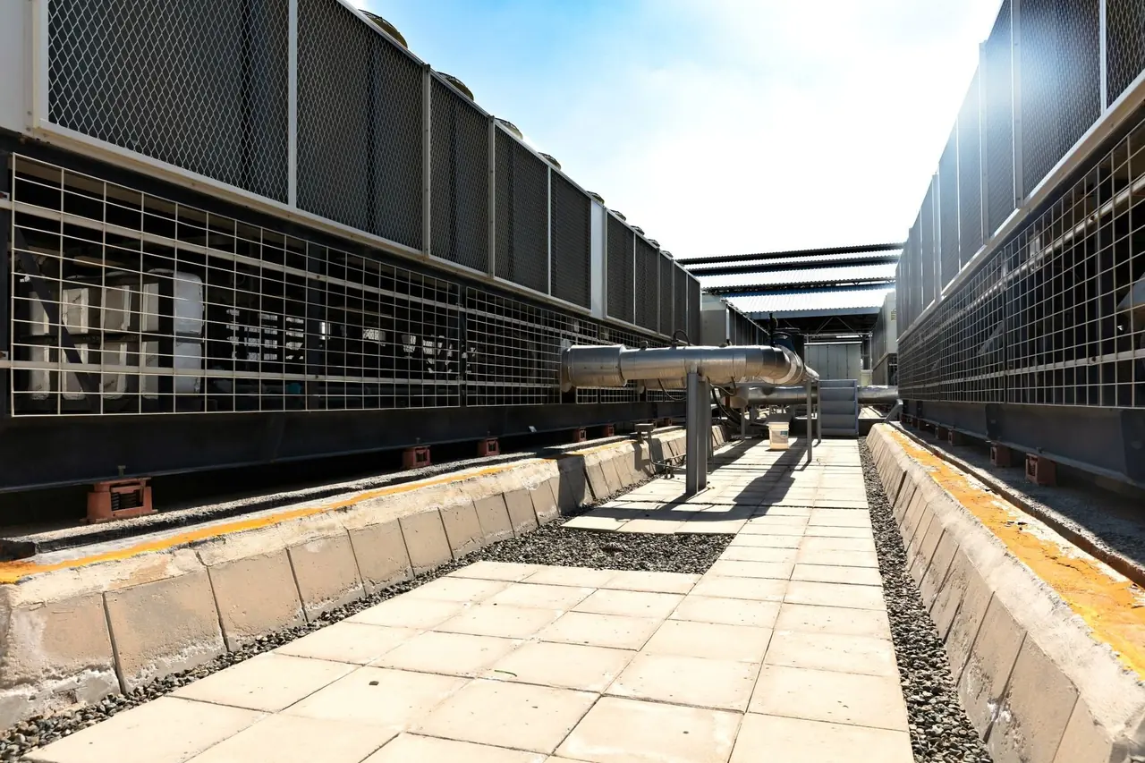 Passerelle entre deux rangées de grands condenseurs sur le toit d'un bâtiment