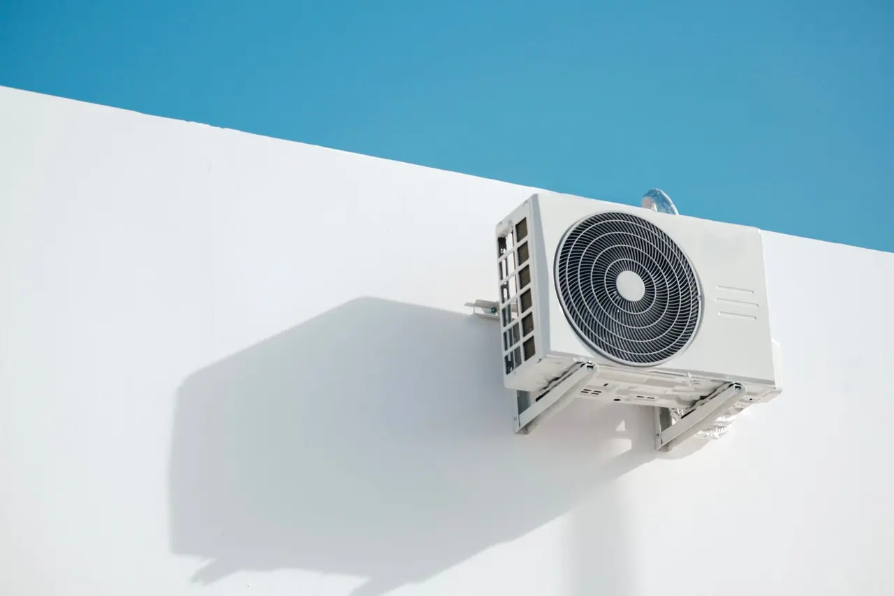 Unité extérieure fixée à un mur blanc sous un ciel bleu