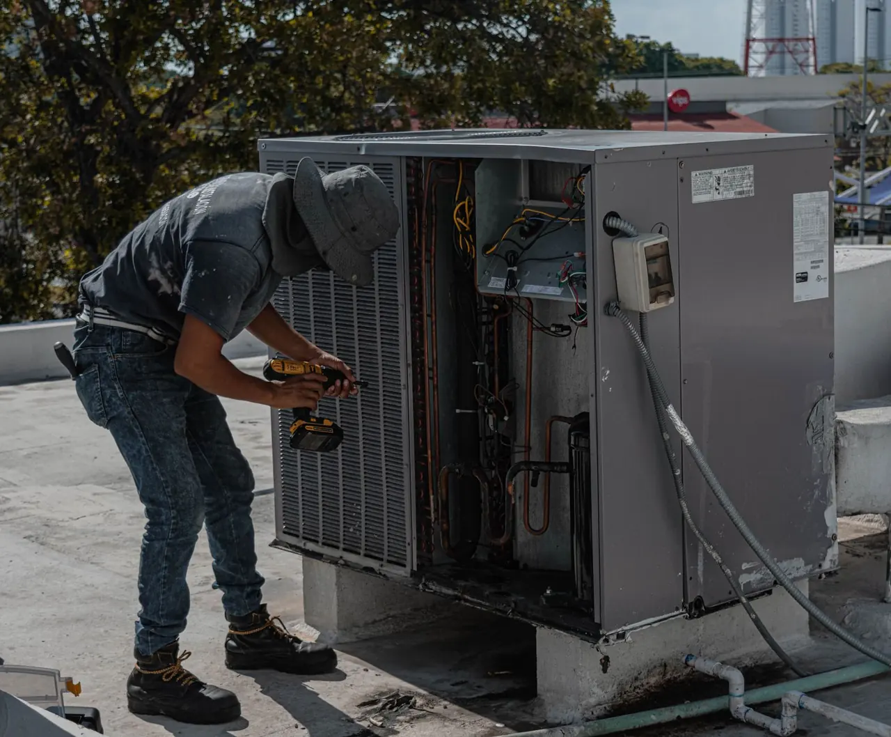 Technicien qui vérifie l'intérieur d'une unité extérieure ouverte, sur un toit